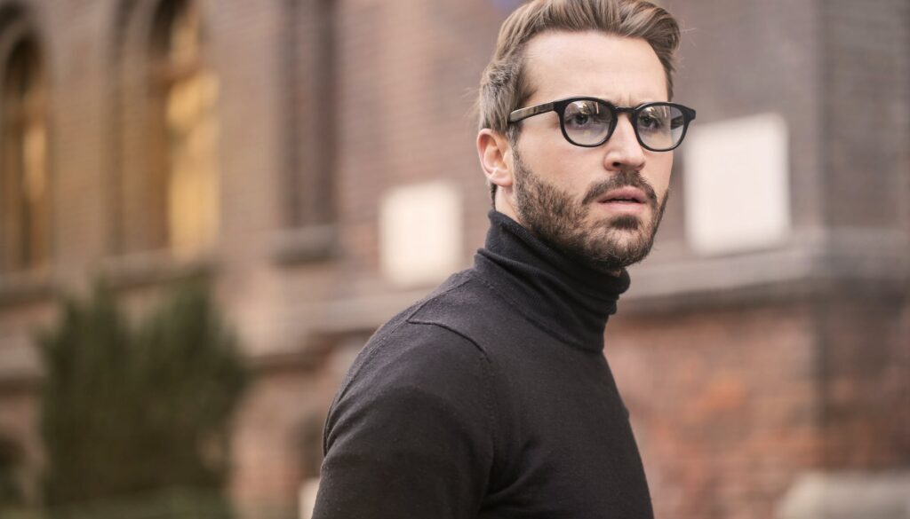 man standing near building white black turtleneck shirt